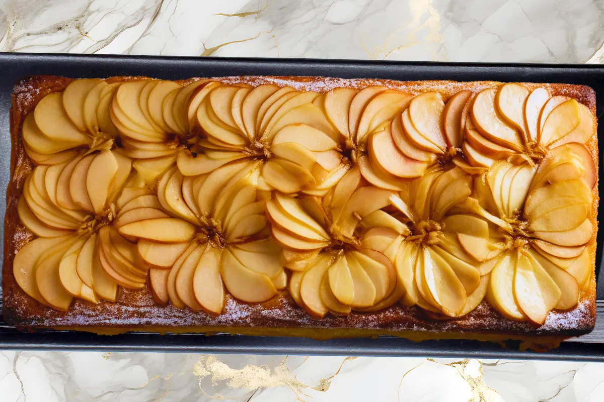 nvisible apple cake on a plate Title: Elegant Slices of Invisible Apple Cake Caption: A delicate and delicious invisible apple cake, ready to serve. Description: A close-up shot of an invisible apple cake, showcasing the thinly sliced apples and the light custard-like batter, emphasizing the texture and flavor of this delightful French dessert. The image captures the airy quality of the cake and emphasizes the use of fresh apples. The focus is on the delicate layers.