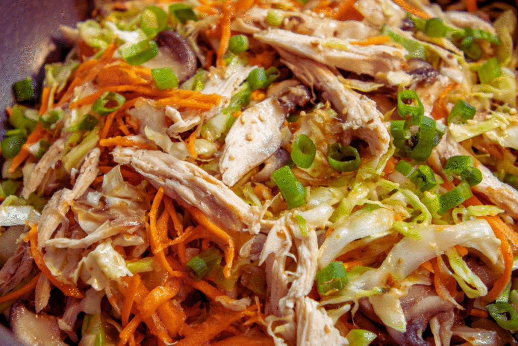 Close-up of classic egg roll filling made with shredded chicken, cabbage, carrots, mushrooms, and green onions.